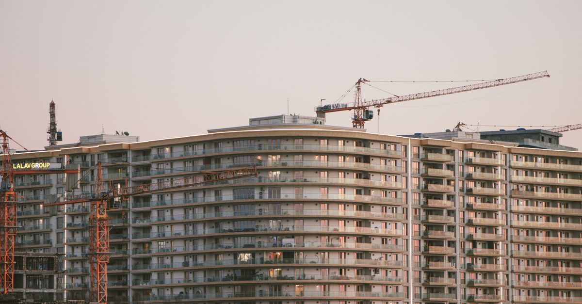 Edificios en construcción con grúas torre recortadas contra el cielo.