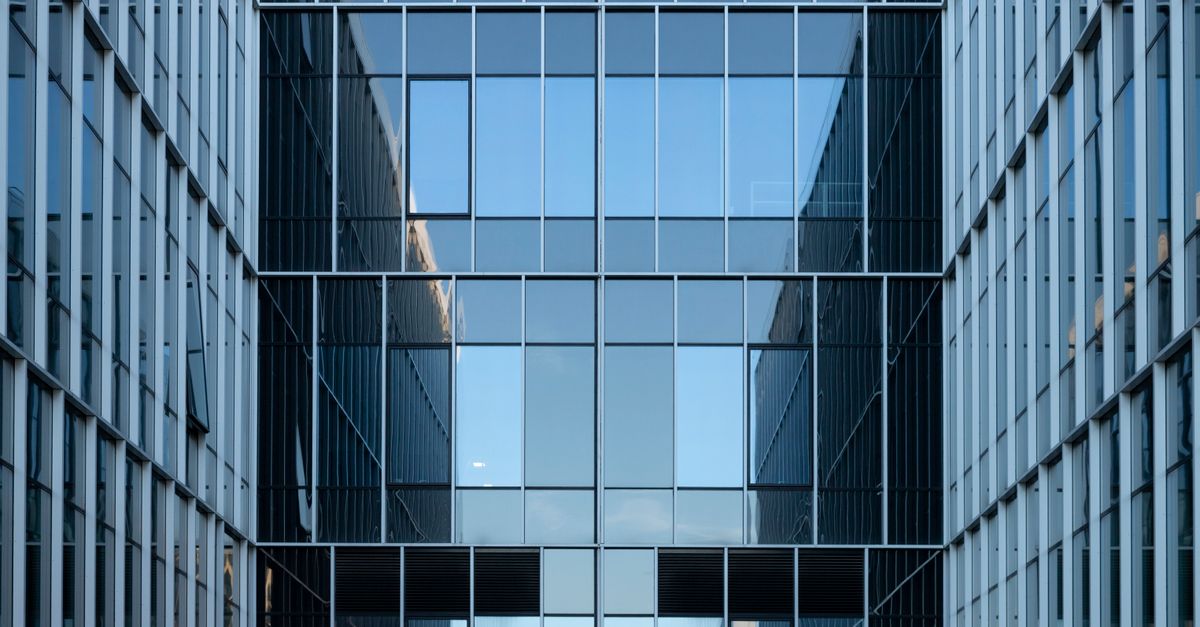 Fachada de cristal reflectante de un edificio corporativo moderno en entorno urbano.
