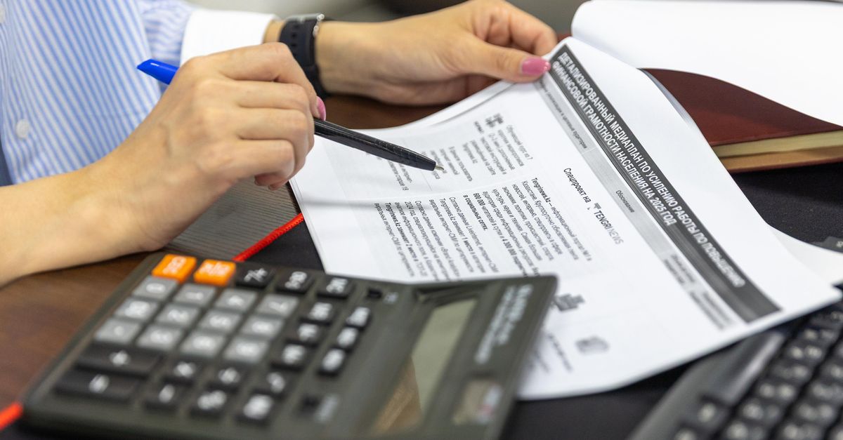 Primer plano de una persona revisando documentos financieros con calculadora y bolígrafo.