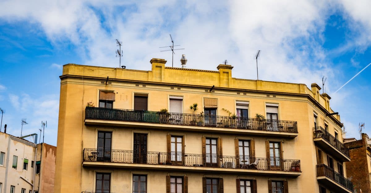 Fachada de un edificio de viviendas del ensanche de Barcelona con balcones y cielo azul.