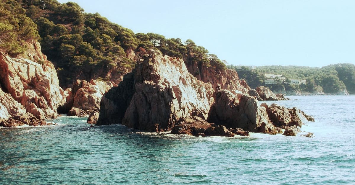 Acantilados rocosos de la Costa Brava sobre el mar azul.