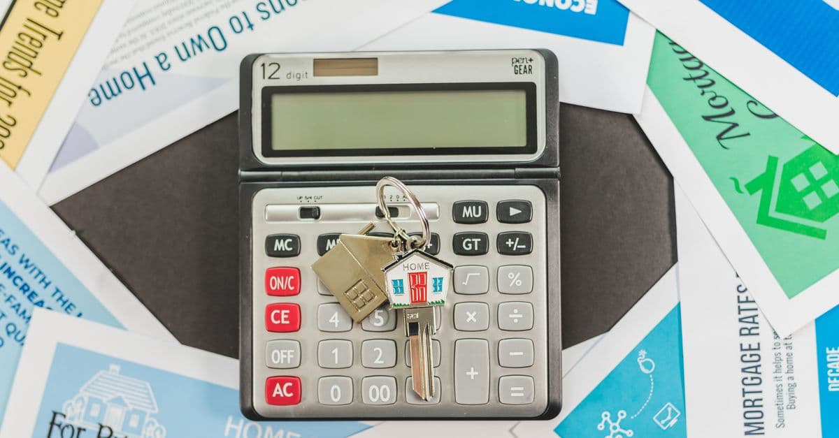 Calculadora, documentos y llaves sobre una mesa durante la compra de una vivienda.