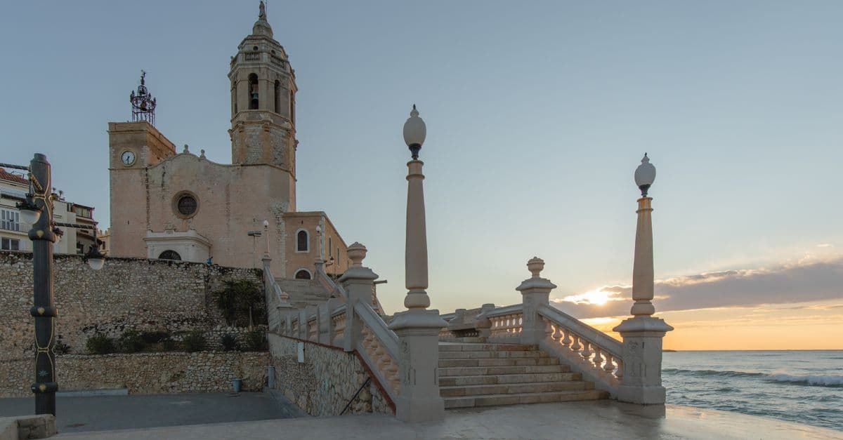 Iglesia de Sant Bartomeu de Sitges sobre el paseo marítimo al amanecer.